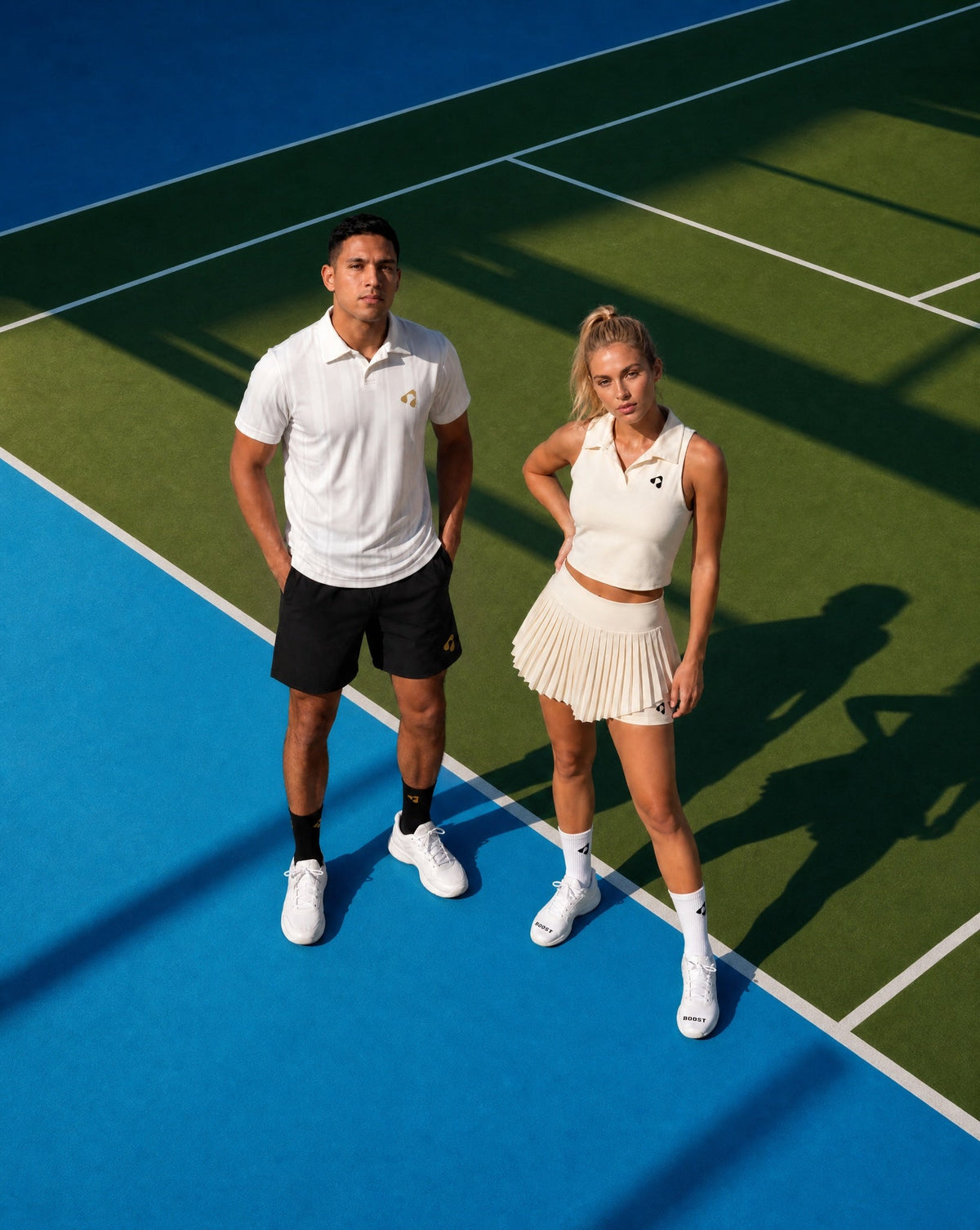 Man and woman wearing Boost Sportswear tennis and padel clothing while standing on a court.