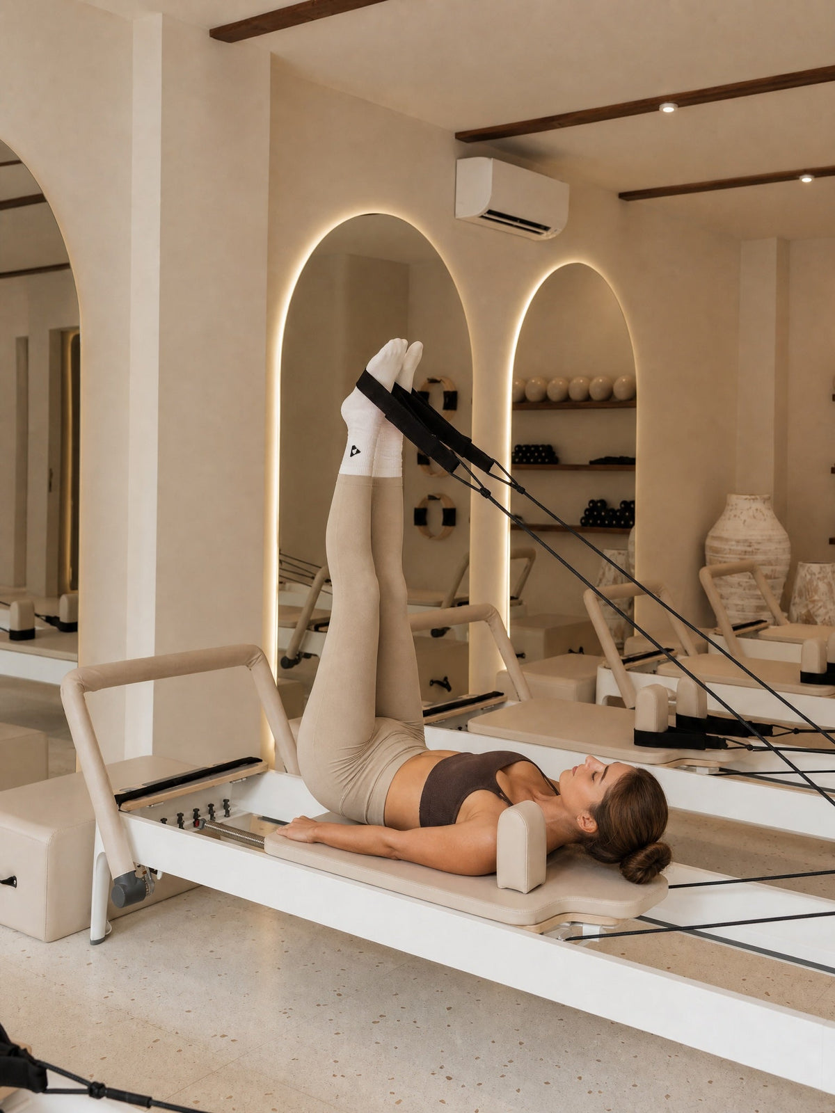 Woman wearing BoostStudio activewear during a Pilates reformer workout.